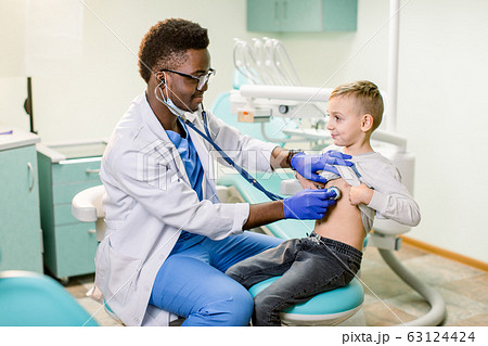 African American Doctor examining child by stethoscope. Happy child boy at the doctor's consultation in hospital. Medical exam at clinic by pediatrician. Pediatric, healthcare and people concept. 63124424