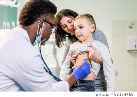 Little boy with mother visiting children's African American doctor with stethoscope in hospital 63124469