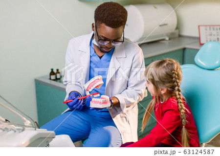 Young beautiful girl in dental office. African children's dentist examines teeth to a child. Young beautiful girl in dental office. African children's dentist examines teeth to a child. 63124587