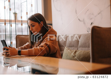 Portrait of attractive woman reading text message on mobile phone at restaurant 63124872