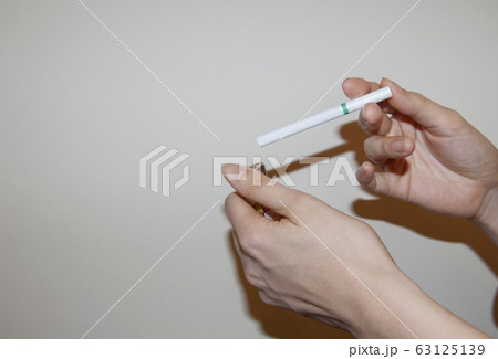 タバコに火をつける女性の手の写真素材