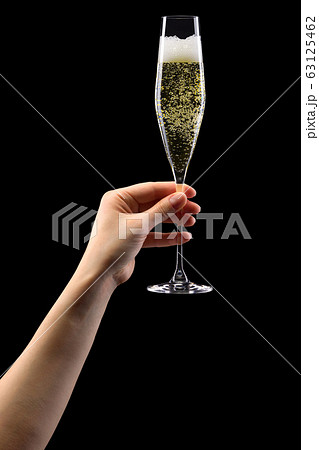 Woman hand holding glass of sparkling champagne isolated on black. 63125462