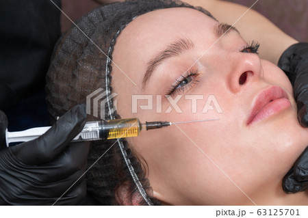 hand with syringe at the patient cheek hand with syringe at the patient cheek 63125701
