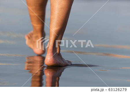 Barefoot woman walking in ocean water waves Barefoot woman walking in ocean water waves 63126279