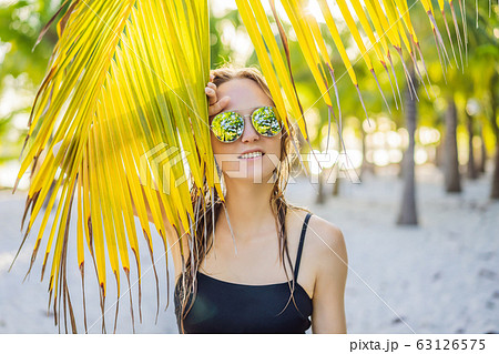 young beautiful woman in swimsuit on tropical beach, summer vacation, palm tree leaf, tanned skin young beautiful woman in swimsuit on tropical beach, summer vacation, palm tree leaf, tanned skin 63126575