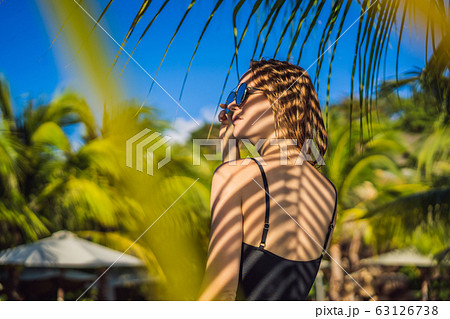 Young woman with the shadow of the palm leaf on her back. Relaxing on the seaside 63126738