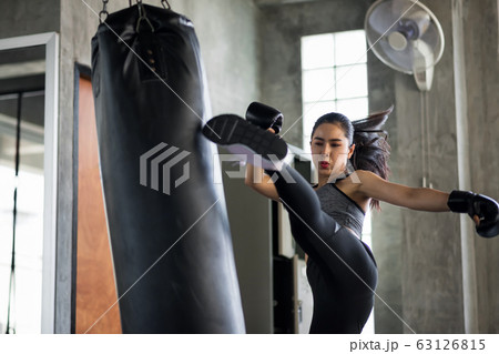 woman jump kick to huge punching bag 63126815