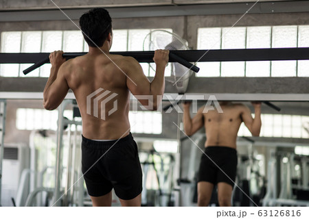 Strong Asian man pull up bar in gym 63126816