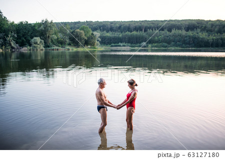 Senior couple in swimsuit standing in lake outdoors before swimming. Senior couple in swimsuit standing in lake outdoors before swimming. 63127180