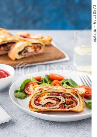 Italian food Pizza roll stromboli with cheese, salami, spinach and red pepper a light background. 63128873