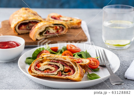 Italian food Pizza roll stromboli with cheese, salami, spinach and red pepper a light background. 63128882