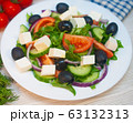 Greek salad with tomatoes, cucumbers and feta cheese with olives on the table 63132313