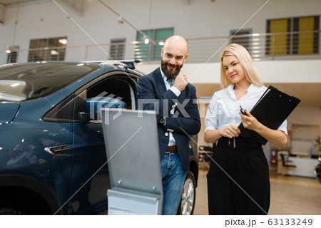 Smiling man and saleswoman in car dealership 63133249