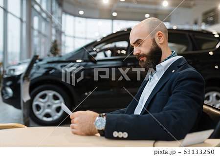 Man looks price on new automobile, car dealership 63133250