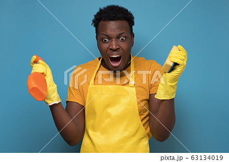 man holding sponges and washing spray being upset not wanting to do cleaning 63134019