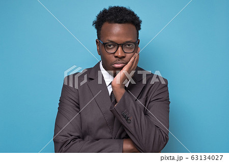 Sad young african american business man in suit and glasses putting hand on head Sad young african american business man in suit and glasses putting hand on head 63134027