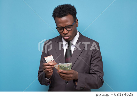 Serious african american business man counting money. Serious african american business man counting money. 63134028