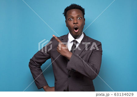 Black african american shocked man point aside and looking at the camera Black african american shocked man point aside and looking at the camera 63134029
