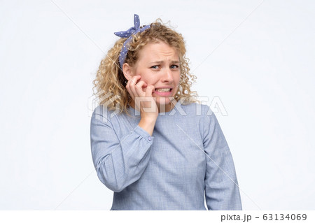 Young nervous girl biting her nails, worried of making mistake Young nervous girl biting her nails, worried of making mistake 63134069