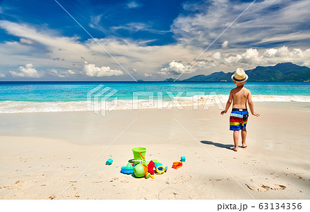 Three year old toddler playing on beach Three year old toddler playing on beach 63134356
