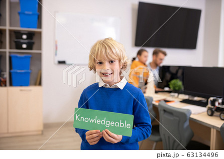 Boy holding green sign with word knowledgeable 63134496