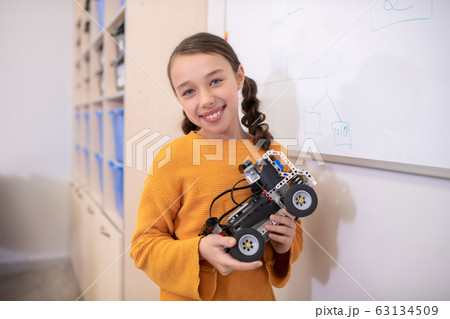 Girl standing at whiteboard and holding buildable car Girl standing at whiteboard and holding buildable car 63134509