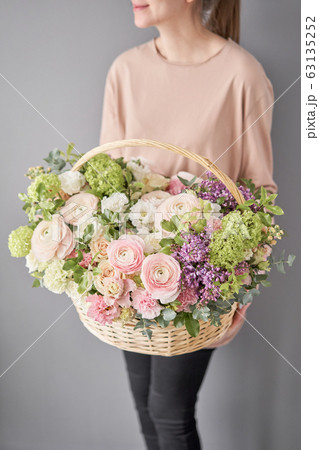 Flowers delivery. Flower arrangement in large Wicker basket. Beautiful bouquet of mixed flowers in woman hand. Floral shop concept . Handsome fresh bouquet. 63135252