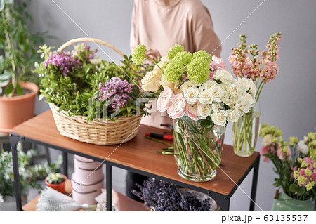 Floral shop concept . Florist woman creates flower arrangement in a wicker basket. Beautiful bouquet of mixed flowers. Handsome fresh bunch. Flowers delivery. 63135537