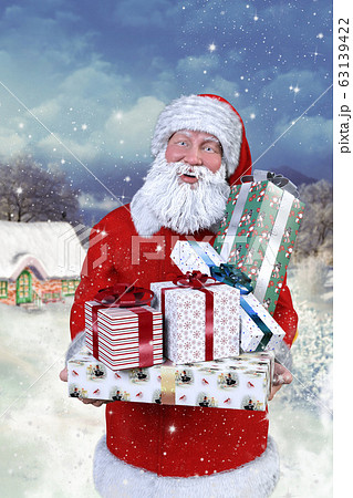 雪景色の中 クリスマスプレゼントを抱えて家の前にいる笑顔のサンタクロースのイラスト素材