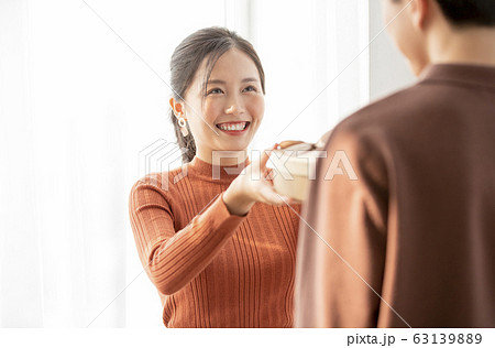 男性にプレゼントを渡す若い女性 63139889