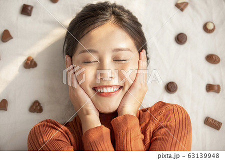 チョコレートと寝転ぶ若い女性 63139948