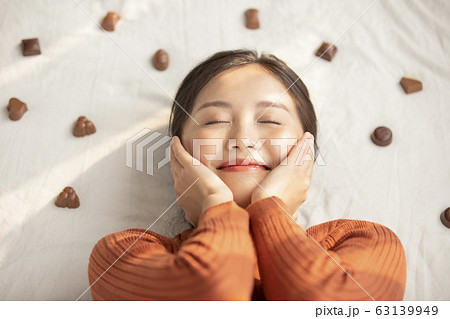 チョコレートと寝転ぶ若い女性 63139949