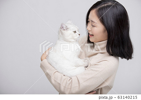 猫を抱きしめる女性のグレー背景ポートレートの写真素材