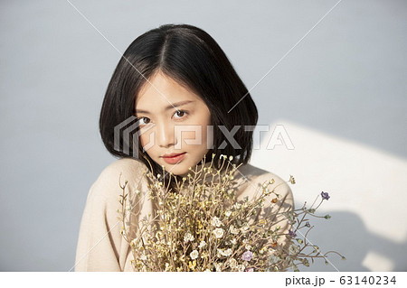 日差しと花を持った若い女性のポートレート 63140234