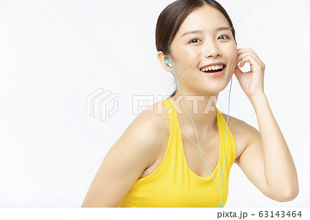 イアフォンをしたスポーツウェアの若い女性 63143464