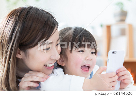 ファミリー スマホを見るママと女の子の写真素材