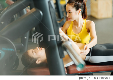 ベンチプレスをする女性とトレーナー 63146501