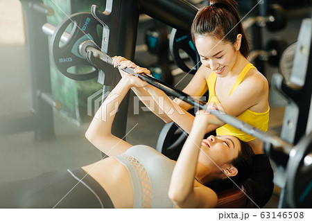 ベンチプレスをする女性とトレーナー 63146508