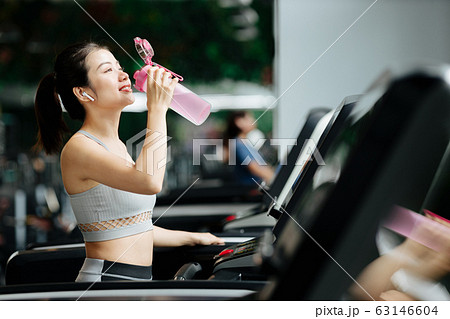 スポーツジムでリラックスをする若い女性 スポーツジムでリラックスをする若い女性 63146604