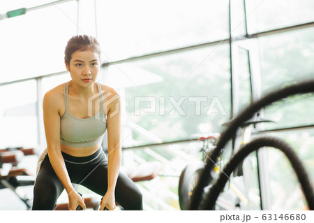 バトルロープでトレーニングを行う若い女性 63146680