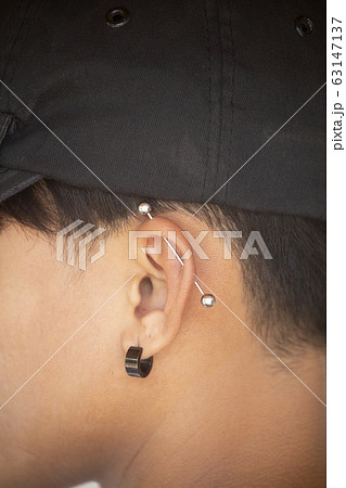 Pierced ear of young boy. 63147137