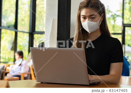 Business Asian young woman working with computer laptop wearing protection mask coughing have fever  63147405