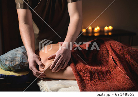 Professional massage of the shoulder and trapezius muscle indoors with cozy dark lighting. Premium massage. Male physiotherapist massage therapist doing upper back massage to a female client 63149955