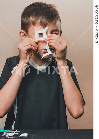 From white paper boy cuts a white square. From white paper boy cuts a white square. 63150566