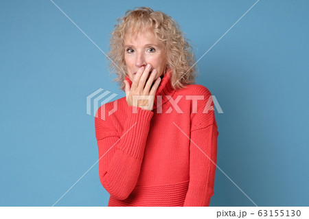 Senior woman giggles covering her mouth with hand 63155130