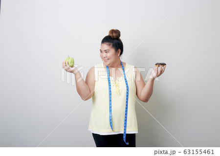 Overweight woman eating food on gray background Overweight woman eating food on gray background 63155461