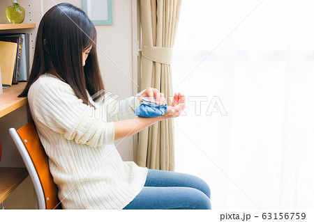 氷のうで手首を冷やす女性 63156759