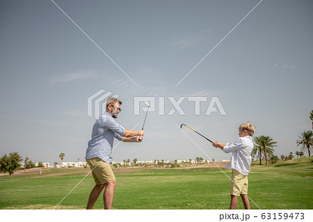 Father has fun and teaches his son to play golf on the green grass 63159473