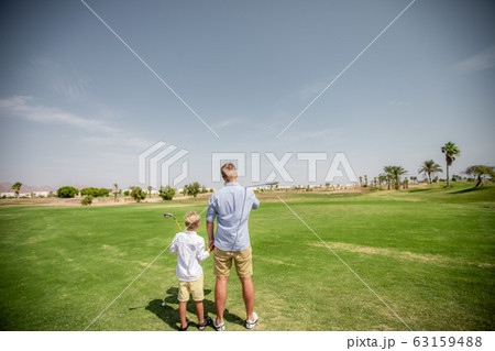 Father has fun and teaches his son to play golf on the green grass 63159488