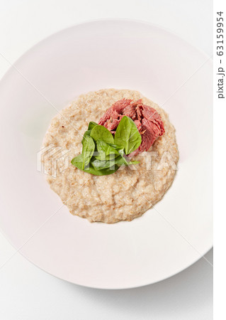 Diet food oatmeal porridge with spinach and ham in the plate. Diet food oatmeal porridge with spinach and ham in the plate. 63159954
